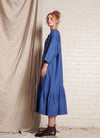 A blue, easy fit, midi-length dress with round neckline, long sleeves, centre front button fastening, flounced hem and embroidered detail at the back made from European pure linen