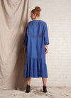 A blue, easy fit, midi-length dress with round neckline, long sleeves, centre front button fastening, flounced hem and embroidered detail at the back made from European pure linen