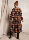 A bronze plaid, midi-length dress with centre front button fastening, round neckline and wrist ties closure made from handwoven ikat cotton